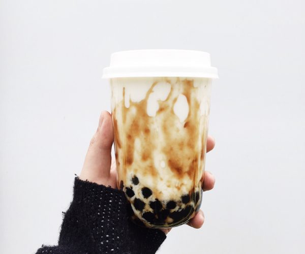 Hand holding cup of dirty milk tea with tapioca pearls